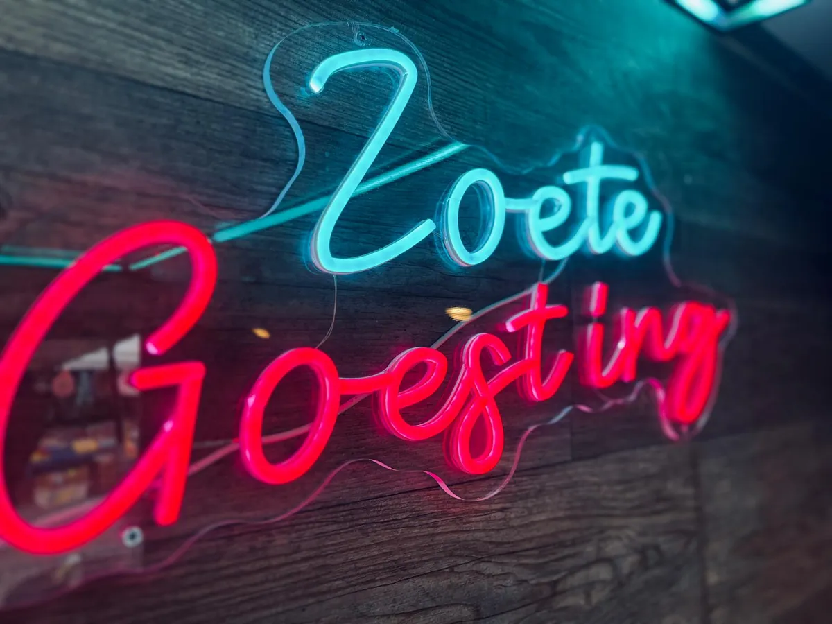 De neonletters Zoete Goesting in blauw en rood op de houten wand binnen in de truck