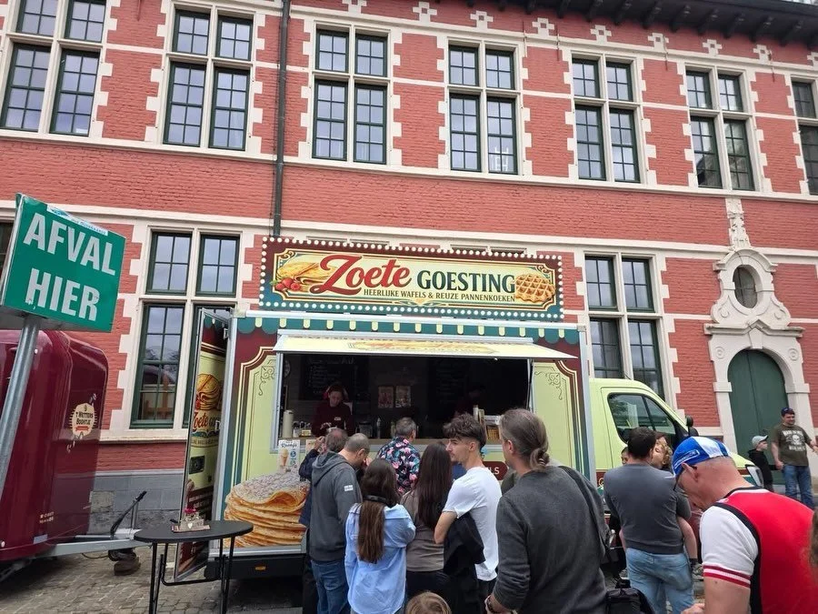 Mensen schuiven aan bij de foodtruck van Zoete Goesting voor een rood bakstenen gebouw